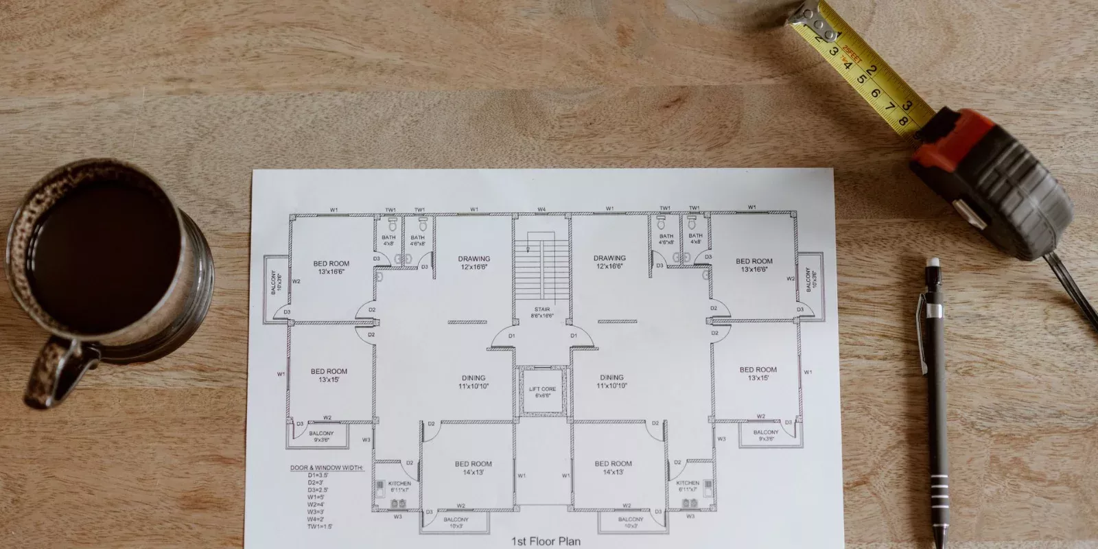 Plano de una vivienda con cinta métrica y lápiz sobre una mesa de trabajo