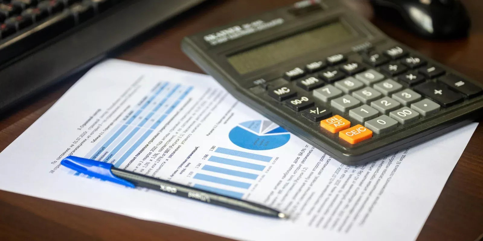 Escritorio con una calculadora, un informe financiero y un bolígrafo