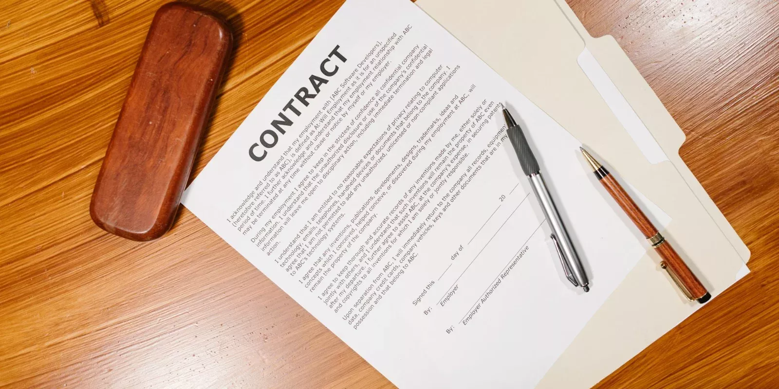Documento de contrato impreso con bolígrafos sobre una mesa de madera