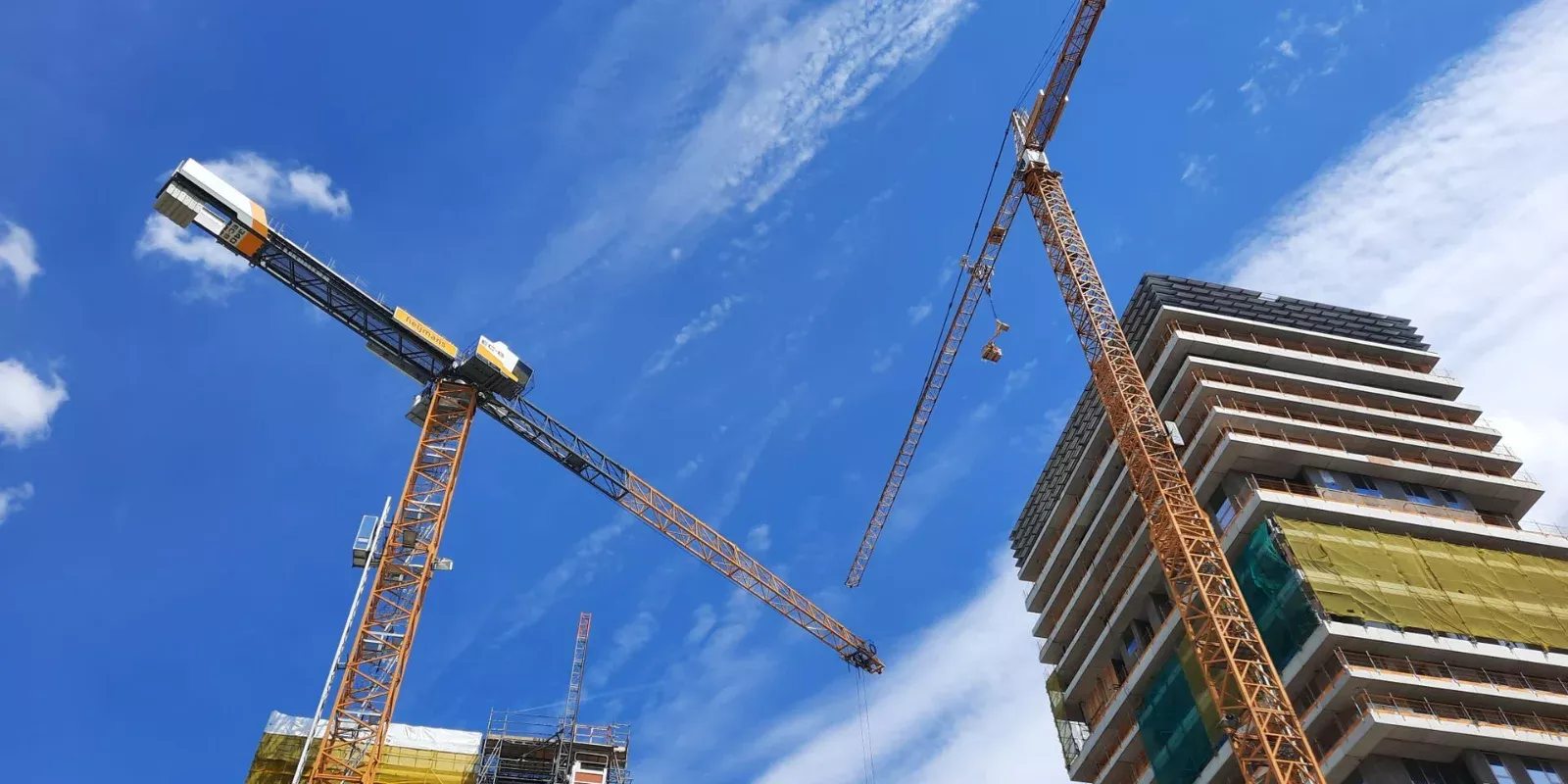 Grúa torre sobre un edificio residencial en construcción bajo un cielo azul